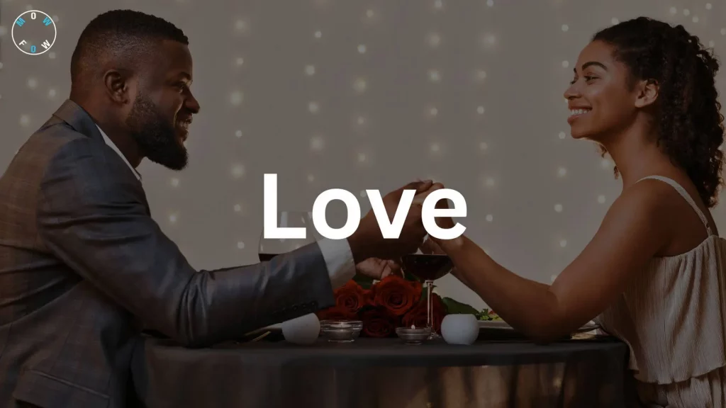 A romantic dinner scene with two people toasting with red wine glasses, their hands touching. The person on the left wears a dark suit jacket, and the person on the right is in a light sleeveless top with curly hair tied up. The table has red roses, lit candles, and plates of food, with string lights in the background creating a cozy atmosphere. The word "Love" in large, bold white text is centered over the image, and a circular logo reading "MOWFOW" is in the top left corner.