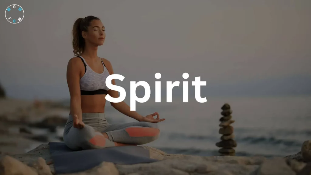 A person meditates on a yoga mat by the seaside, sitting cross-legged on a rocky surface. They wear a gray sports bra and leggings with coral accents. A stack of stones is to their right, with a calm ocean and muted sky in the background. The word "Spirit" is in large white text across the center, and a "MOWFOW" logo is in the top left corner.
